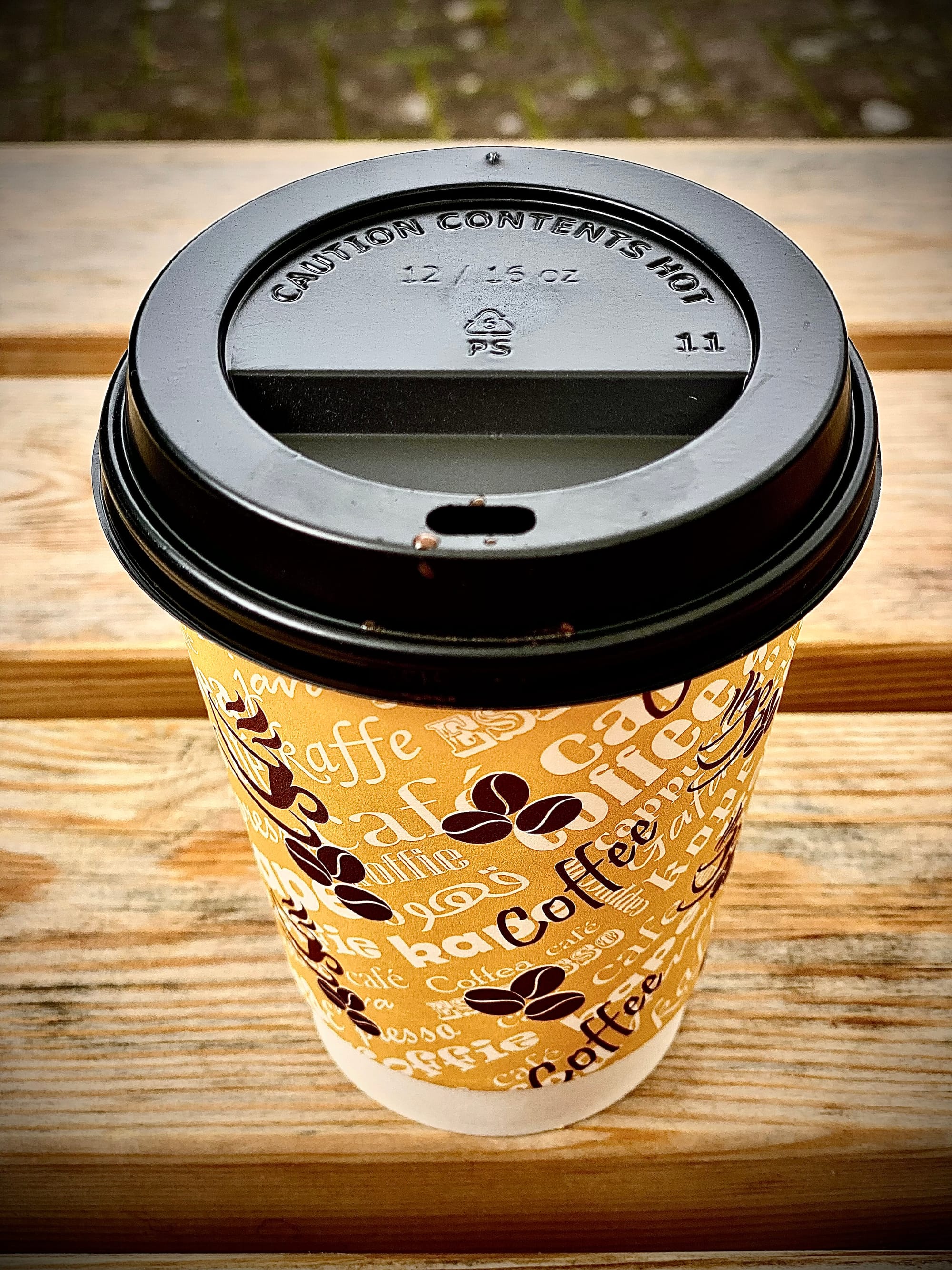 A take-away coffee-cup with a black plastic lid.