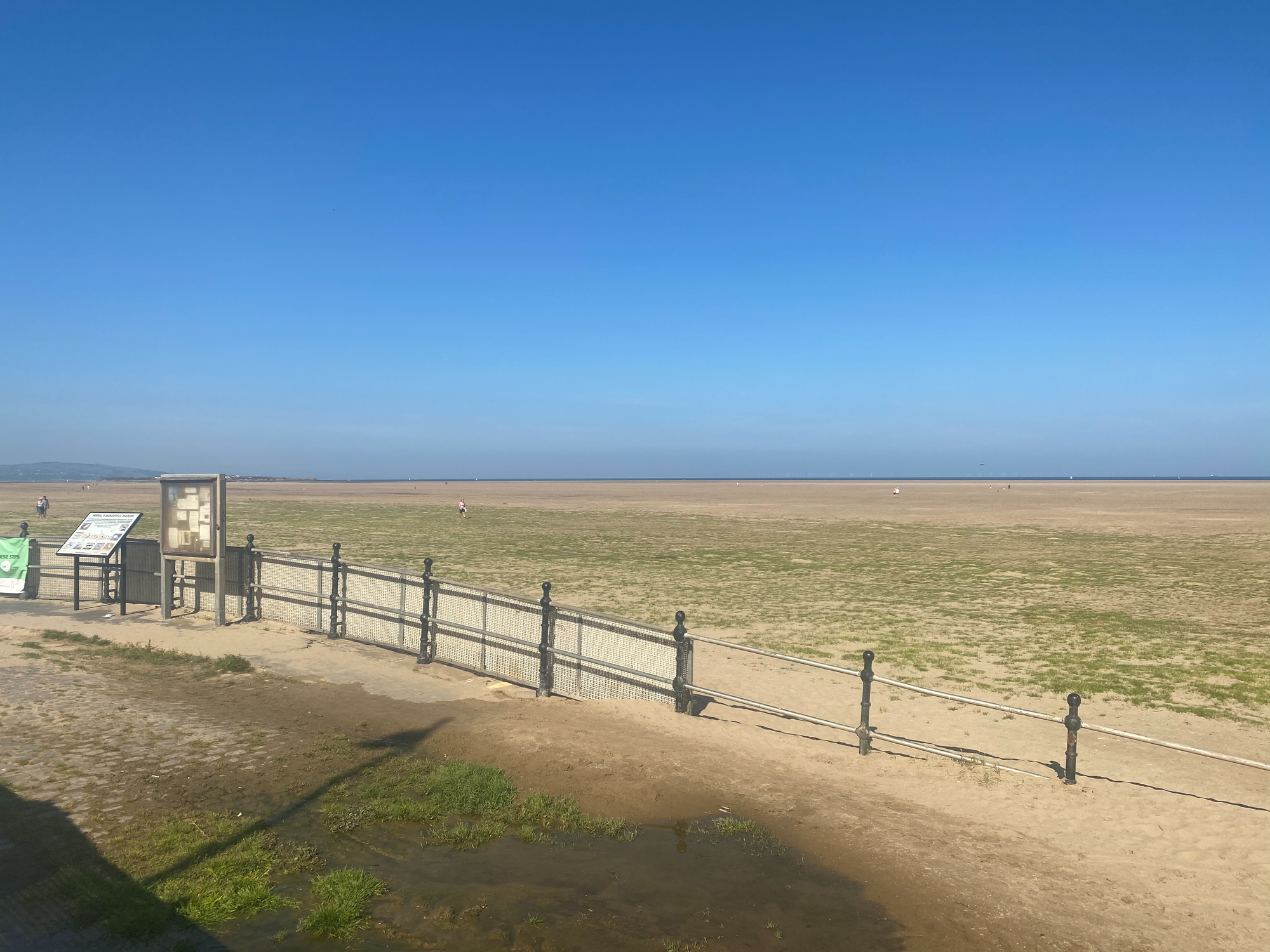 A beach stretches out into the distance.  Railings disappear into the sand.
