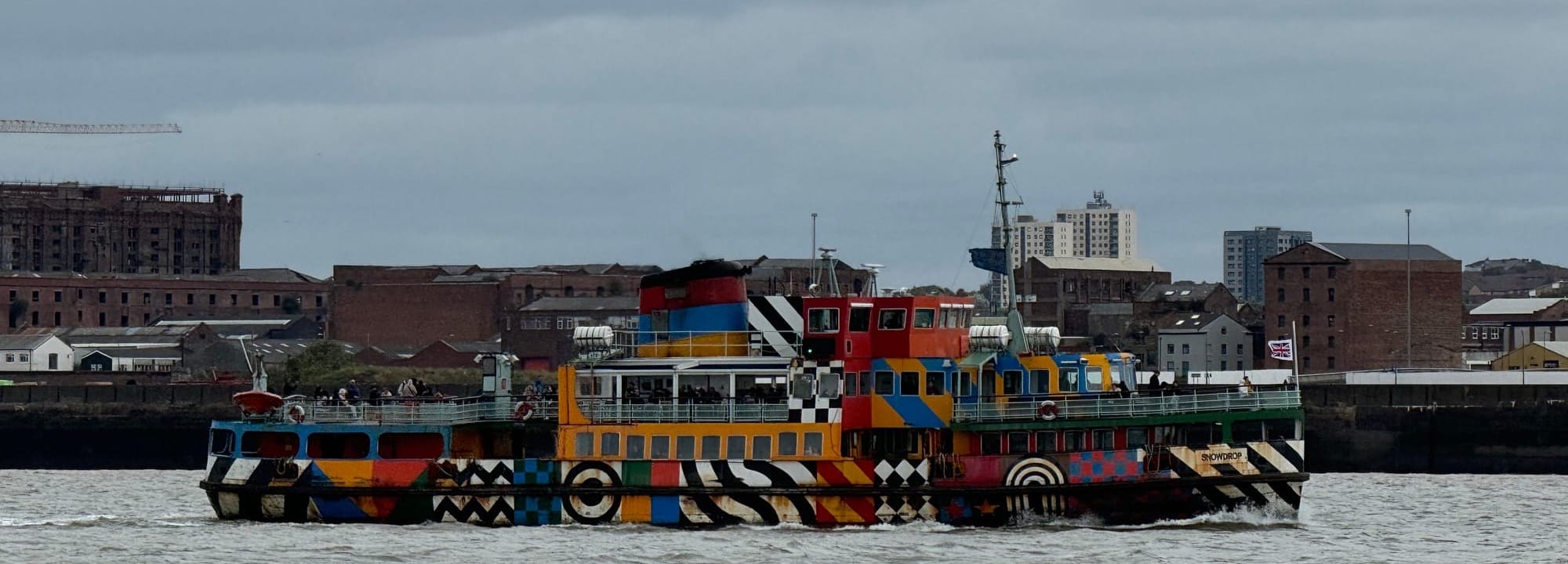 A Mersey Ferry in the middle of the Mersey.  It is painted in multiple colours and looks very jazzy!